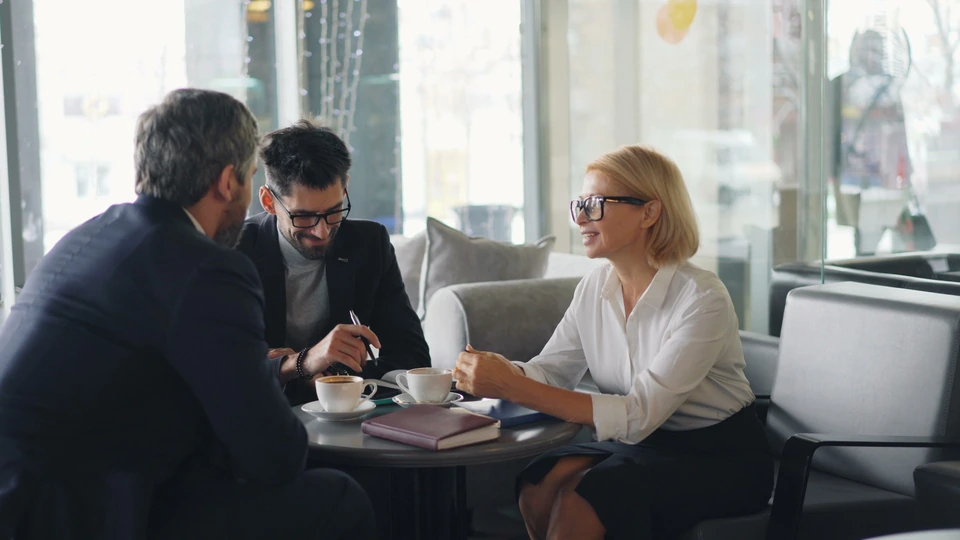 Three people discussing documents around a table.