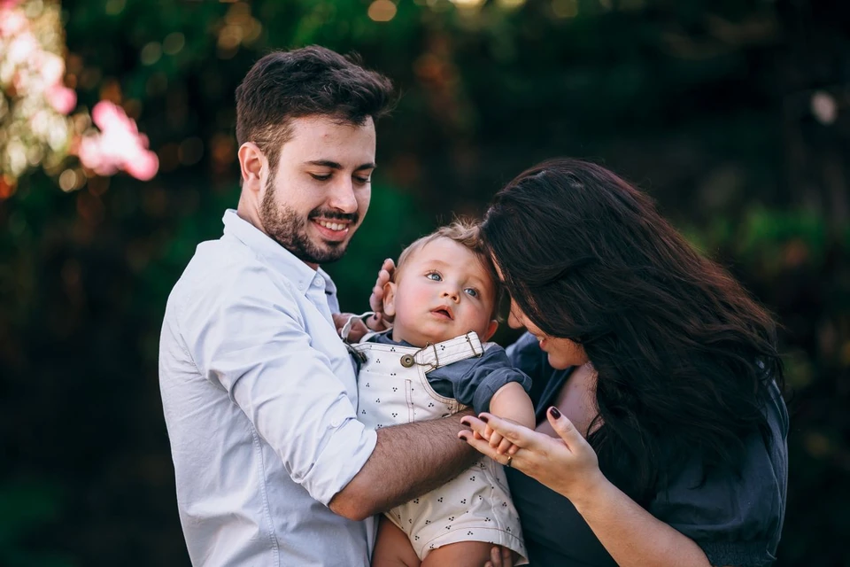 Parents holding their young child outdoors.
