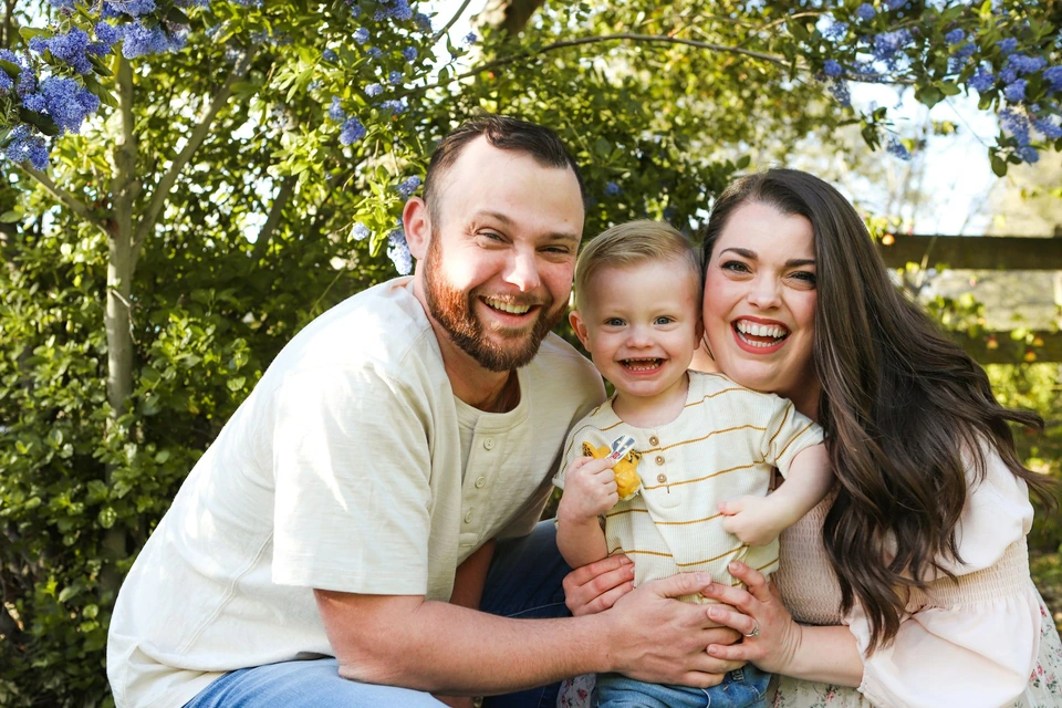 Parents with their young child in a garden.