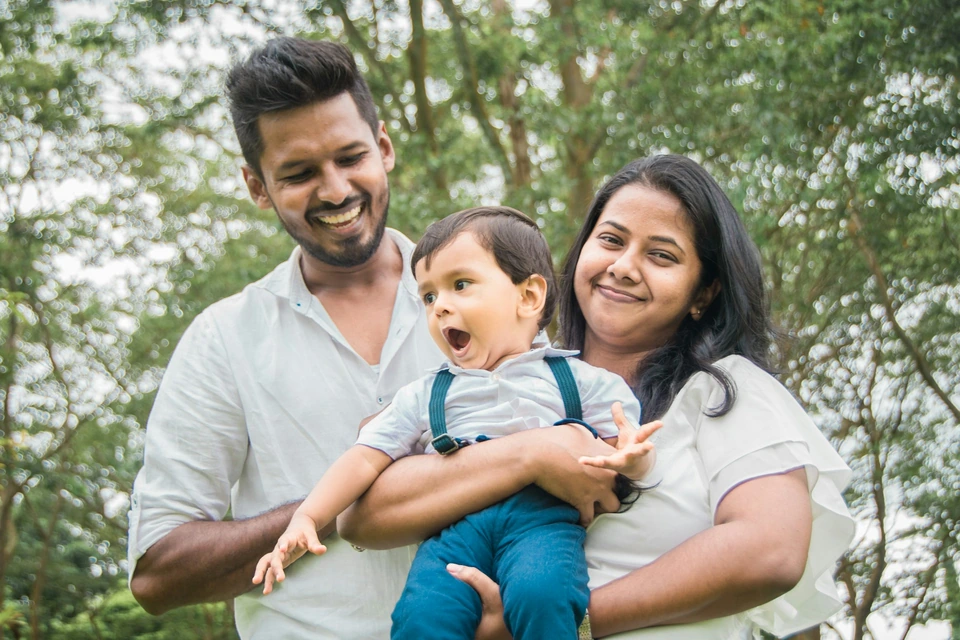 Parents holding their young child in a garden.